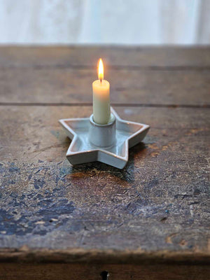 This simple Star Candle Holder with White Glaze, lends a quiet elegance and clean design to add instant ambience to any room. This ceramic taper holder is equal parts modern simplicity and organic imperfection. Features a white glaze finish. Fits regular size tapers (candle not included)