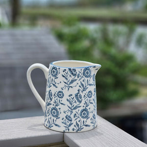 This charming White and Blue Floral Pitcher brings timeless farmhouse elegance to your kitchen or dining table. Crafted with a creamy white base adorned with delicate blue floral motifs, its classic pitcher silhouette evokes the warmth and simplicity of country cottage living. Perfect for serving beverages at gatherings, displaying fresh flowers, or adding a nostalgic touch to your home decor, this piece captures the heart of cottage style