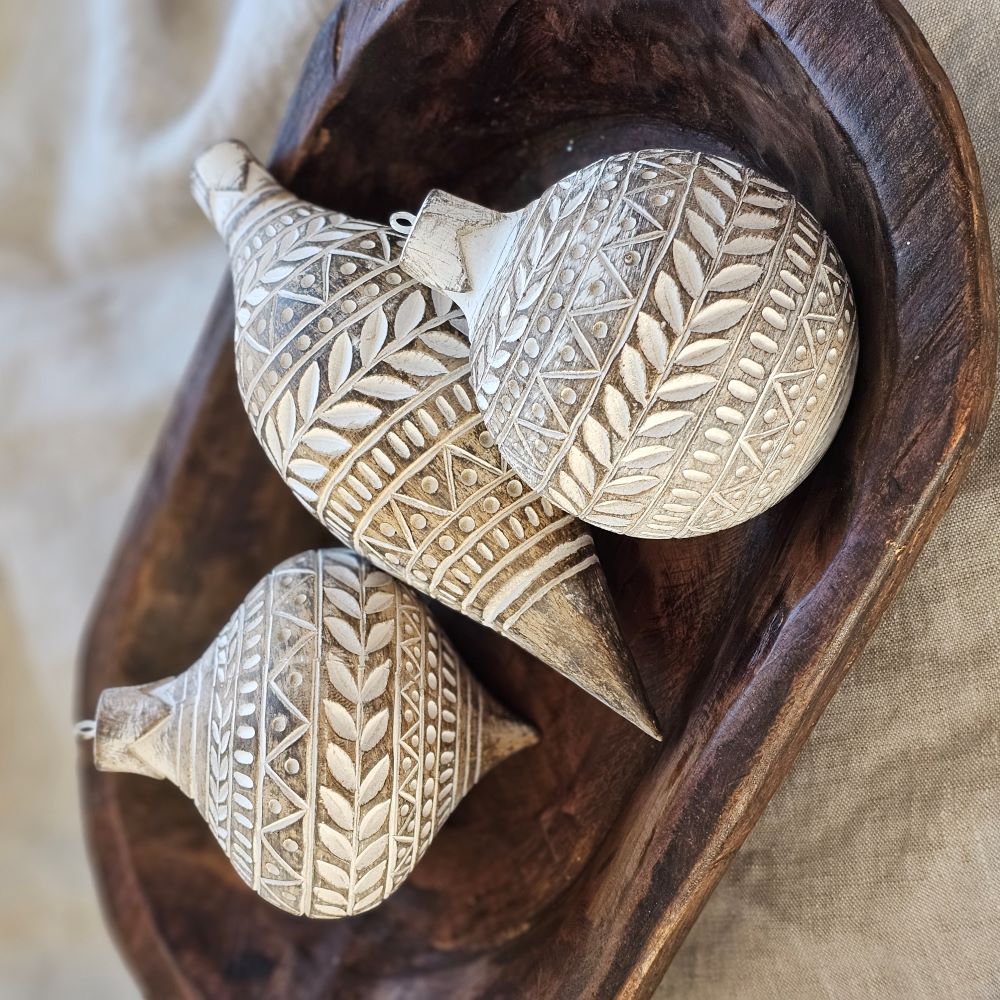 These decorative Distressed White Carved Wood Style Ornaments add a unique touch to bowls and displays. Like snowflakes, each has a different festive white design that really pops against the underlying rustic wood color grain. Includes metal loop for hanging. Made of resin/stonepowder. Set of three