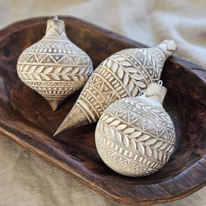 These decorative Distressed White Carved Wood Style Ornaments add a unique touch to bowls and displays. Like snowflakes, each has a different festive white design that really pops against the underlying rustic wood color grain. Includes metal loop for hanging. Made of resin/stonepowder. Set of three