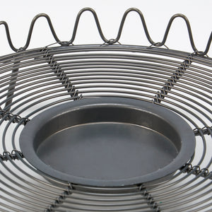 The French Wire Trivet Style Candle Holder merges vintage charm with primitive farmhouse simplicity. Featuring a gray metal wire base with a graceful wave-pattern border, it is inspired by old French wire cooling racks and trivets. 