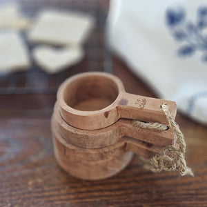 Bring rustic farmhouse style to your cooking with this Wood Measuring Cup, Set of Three. These hand-crafted wood measuring cups complement any kitchen style. Made of Acacia wood, each is unique, no two are exactly alike! The natural wood has a water-based, food safe seal. For longer term protection you can oil the cups with a mineral based oil, which will darken the wood and enhance the natural grain. Not suitable for the dishwasher or microwave. Set of three includes: 1/4 cup, 1/3 cups and 1/2 cup.