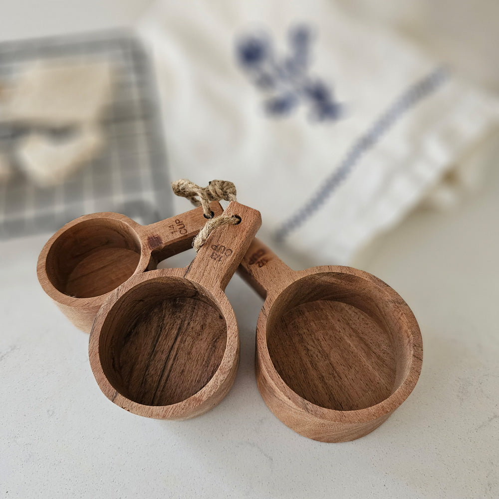 Bring rustic farmhouse style to your cooking with this Wood Measuring Cup, Set of Three. These hand-crafted wood measuring cups complement any kitchen style. Made of Acacia wood, each is unique, no two are exactly alike! The natural wood has a water-based, food safe seal. For longer term protection you can oil the cups with a mineral based oil, which will darken the wood and enhance the natural grain. Not suitable for the dishwasher or microwave. Set of three includes: 1/4 cup, 1/3 cups and 1/2 cup.