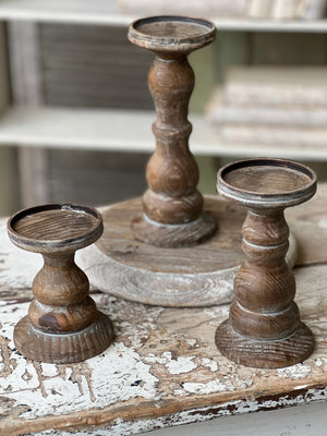 Create an inviting atmosphere in any room with these Rustic Wood Pillar Candle Holders. Crafted from solid wood with turned bases, they bring an old-world charm and rustic ambiance to your mantle, dining table or dresser. Ideal for mixing and matching, the set of three in different sizes makes a great centerpiece.Set of three.