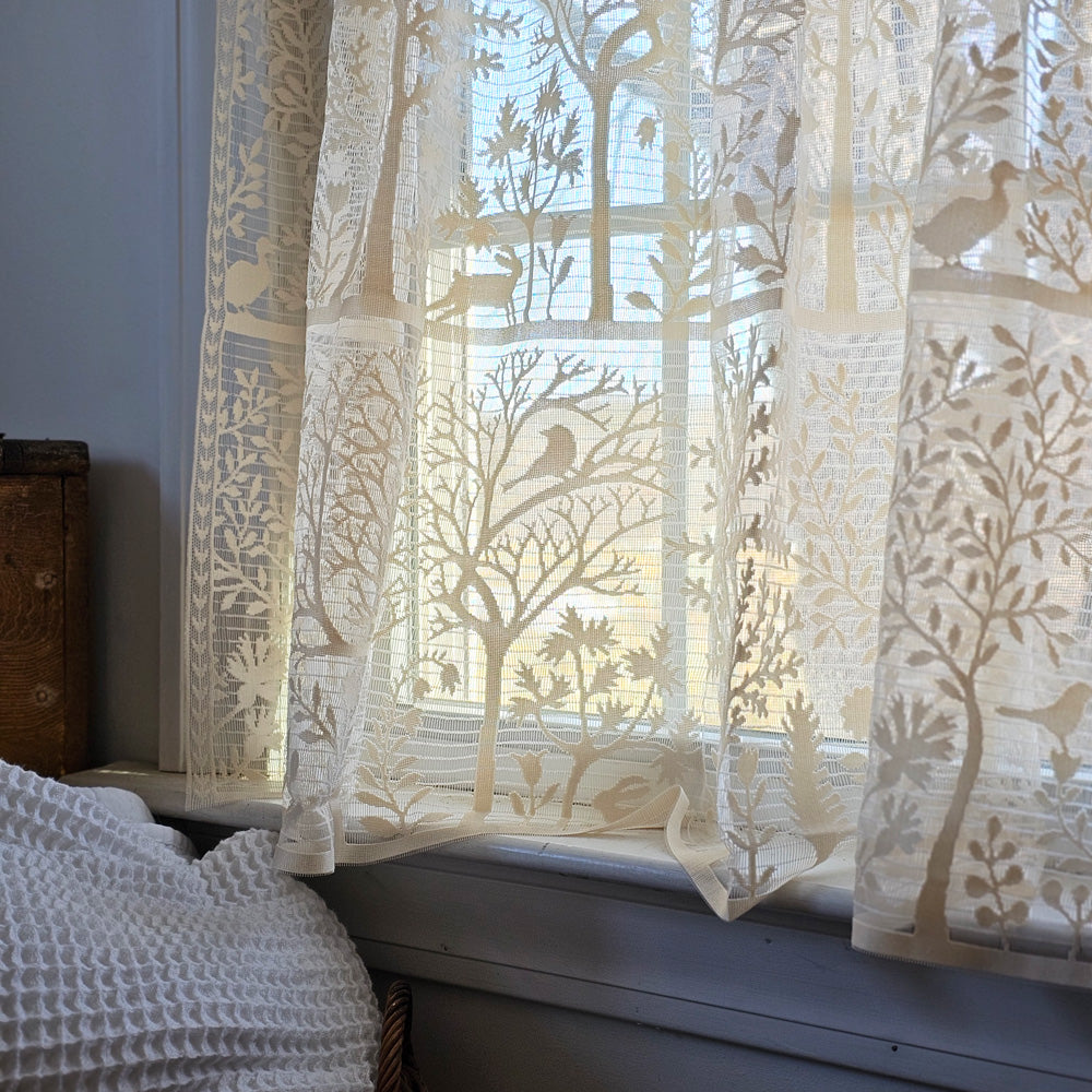 Add instant charm to any room in your farmhouse with the Woodland Antique White Lace Tier Curtain. In a celebration of nature and folk art, assorted flora and fauna come together in this popular tree of life design. The design includes bunnies, birds, geese and trees. This tier curtain is artfully crafted of sheer, washable lace. Made in the USA