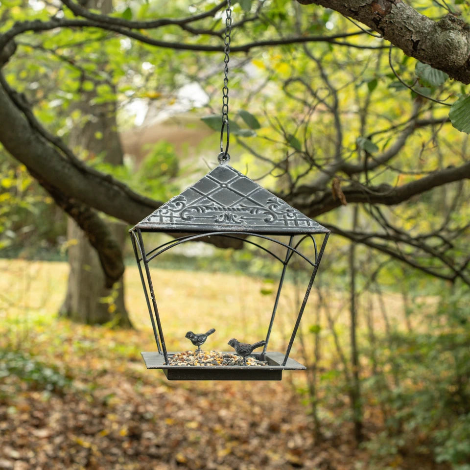 The Carriage House Bird Feeder adds sweet vintage charm to any garden space. Features and aged black metal house and two little bird figures with a chain for hanging. 
