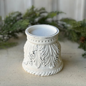The Ancienne Candle Holder features romantic curves and an aged, chippy white paint look that is familiar to today’s vintage cottage style. This resin pillar candle holder has an ornate carved leaf design and detailing around the base. The Ancienne is perfect for adding a bit of shabby chic flair to any tabletop or bedside table. Candle not included. 4.85"Diam x 4.5"H