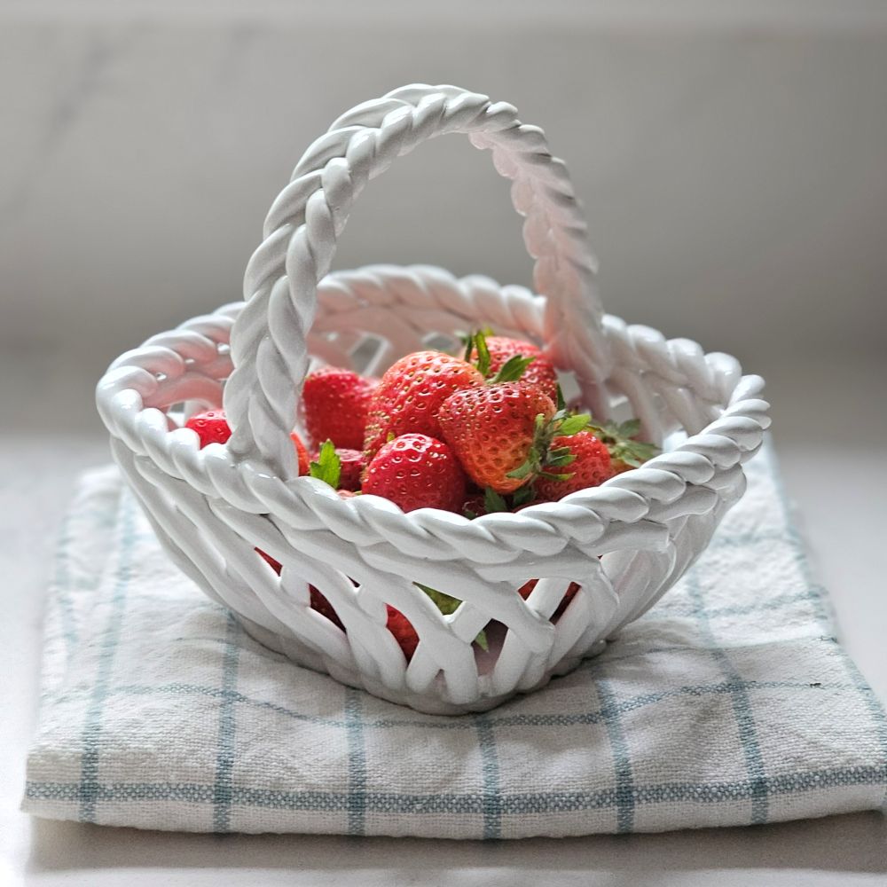 White woven basket filled with strawberries on a checkered cloth