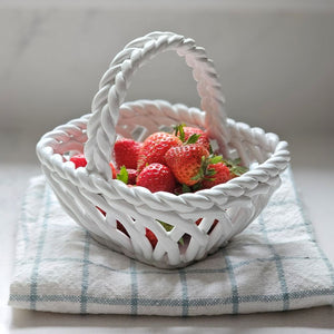 White woven basket filled with strawberries on a checkered cloth