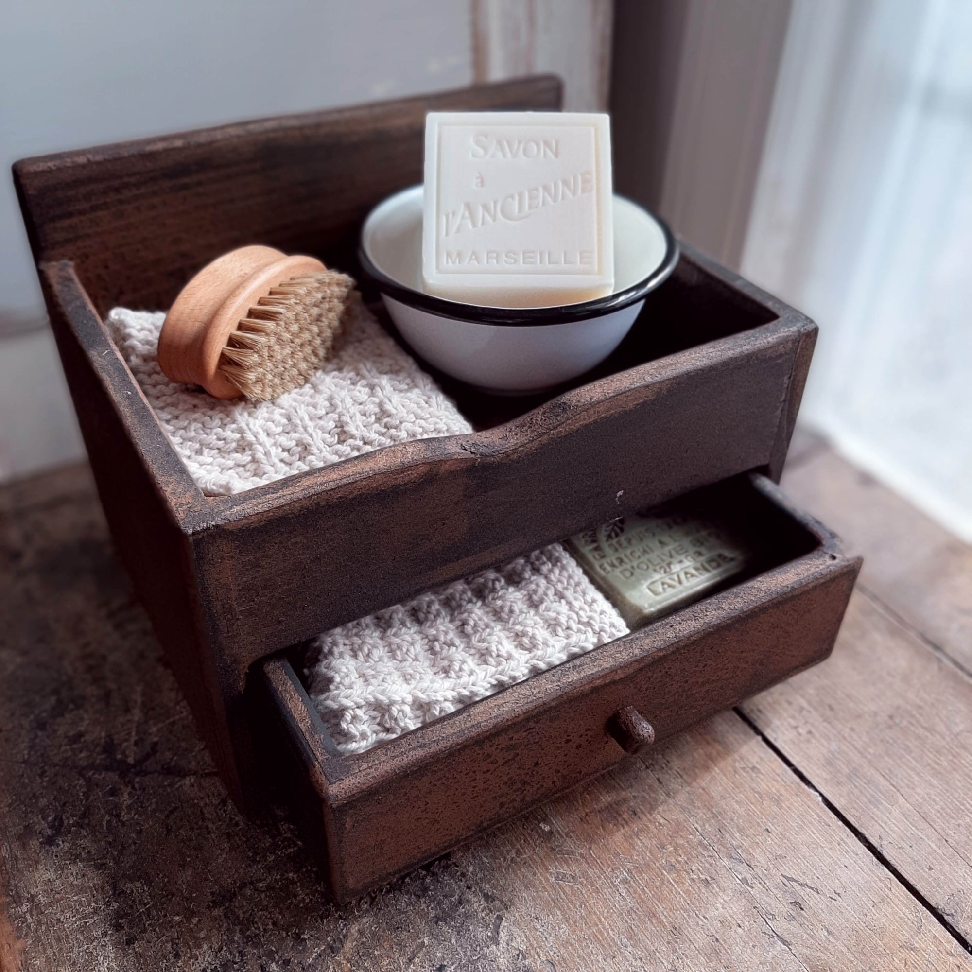 Our Wood Counter Cabinet with Drawer is a versatile piece for farmhouse organization. Use on the kitchen counter to create a mini coffee bar, storing k-cups while keeping sugar and other essentials on the top tray. Add to a vintage farmhouse bath to stash away soaps. It makes a great storage box for craft or office supplies, jewelry and more. This sturdy wood cabinet features a tray on top and one drawer. It has a distressed, aged wood finish.