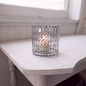 Add a bit of magical ambiance with our Clear Glass Mosaic Candle Holder. Features crystal clear glass that is hand cut and laid into intricate patterns and offset by a dark black grout in this updated take on mosaic. The glow of candlelight through the cut pattern is dreamy. Can also be used a vase. 4" Diam x 4"H