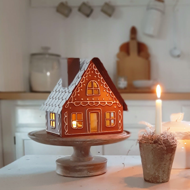 Sugar and spice, everything nice! This Gingerbread Cottage Luminary is ready to spice up any tabletop or shelf. Simply place a candle or fairy lights inside through its latched access door on the back for a magical glow. The gingerbread house can be placed on a table or hung with its keyhole hanger. Candle and light not included. Made of metal. 8¾''W x 5''D x 8½''H