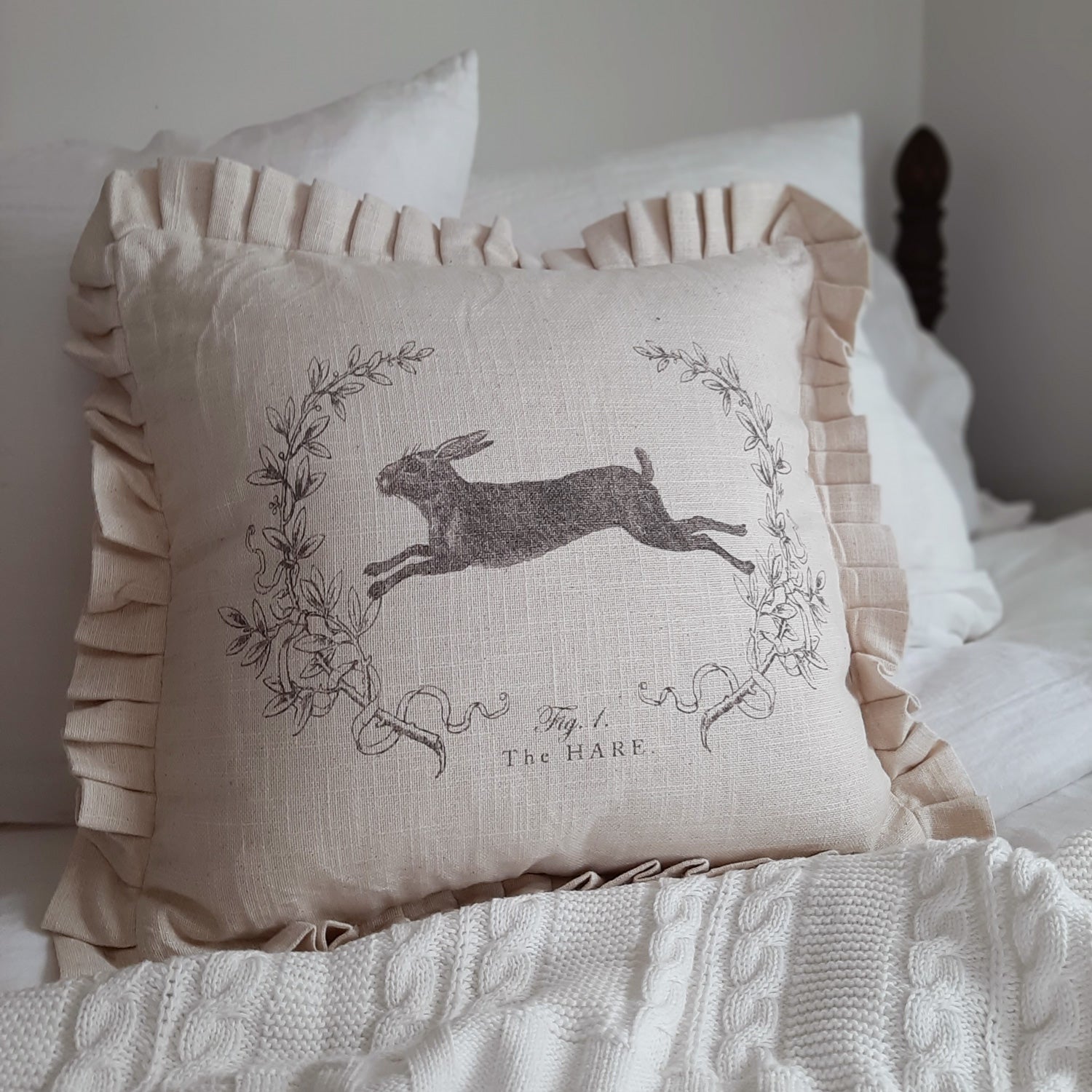 This Linen Style Hare Pillow with Ruffles lends a vintage charm to any room. Made of 100% cotton, this super soft pillow features a leaping bunny illustration on a rustic linen look fabric that has a warm oatmeal color. It instantly brings a cozy, down-to-earth sensibility to any farmhouse. The sweet ruffled edging lends a cottage feel.  Backside features a zippered closure. 100% cotton. 16"L x 16"H. Pillow insert made of 100% Polyester.
