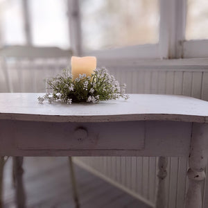 Add sweet cottage charm to any room with our Little Lassie Wreath and Candle Ring. This faux floral wreath is lush with fresh greens and packed with tiny soft white foam flowers. Hang from a small hook or use as candle ring with pillar candles.  10" round 3” inner