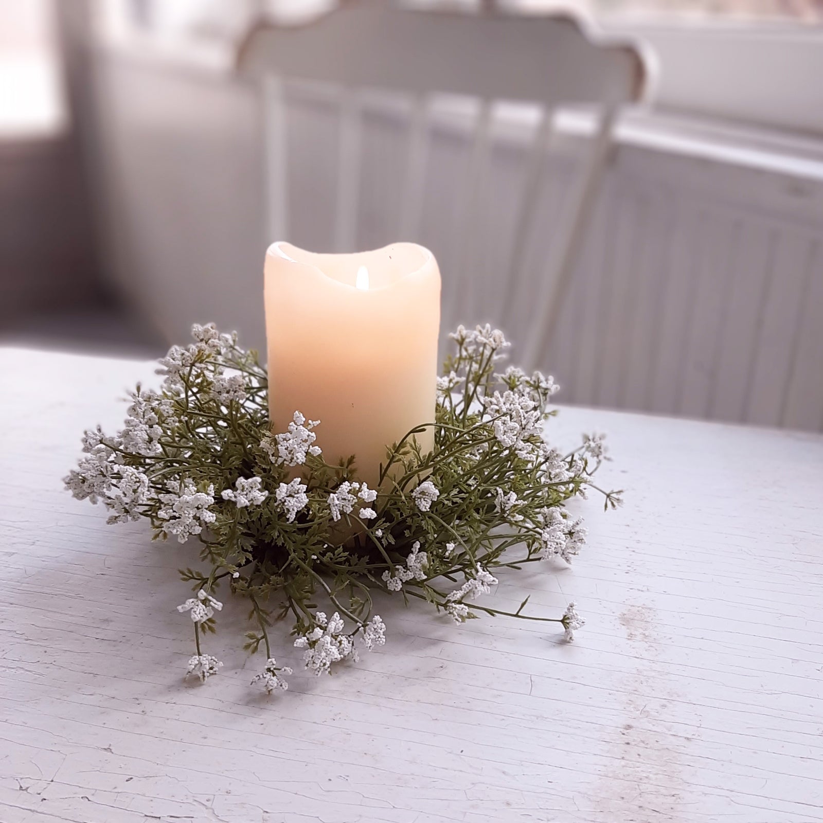 Add sweet cottage charm to any room with our Little Lassie Wreath and Candle Ring. This faux floral wreath is lush with fresh greens and packed with tiny soft white foam flowers. Hang from a small hook or use as candle ring with pillar candles.  10" round 3” inner