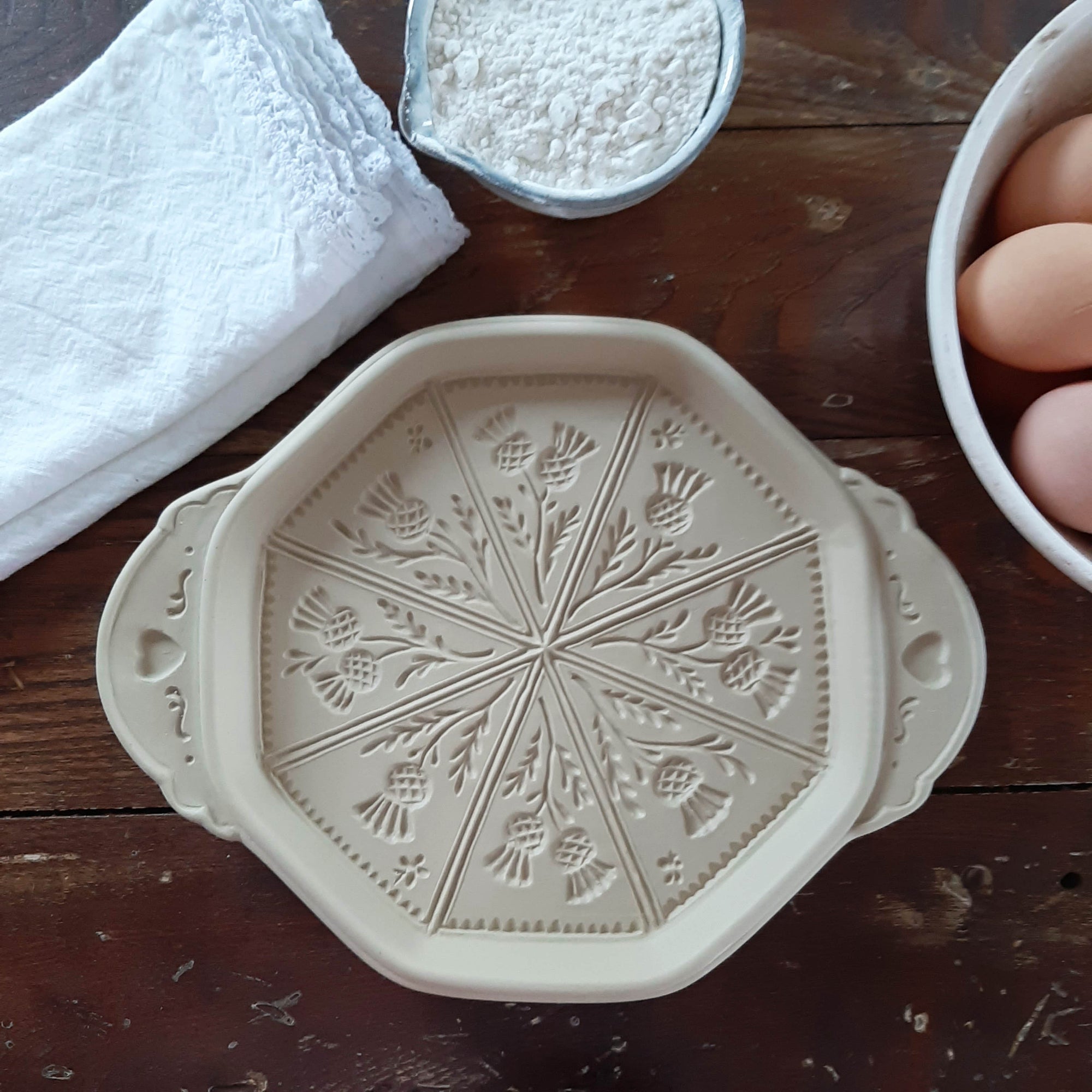 This beautiful Stoneware Shortbread Pan with will have you baking impressive shortbread cookies to amaze guests and give as gifts.

Shortbread’s popularity dates back to the 16th century and its refinement is credited to Mary, Queen of Scots. Shortbread was once considered an expensive luxury for special occasions and weddings.

Crafted in the USA, this natural stoneware pan lends a beautiful, old-fashioned touch to open shelves when not in use. It creates stunning triangular wedges, which were known as "pe