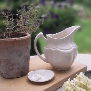 Reminiscent of old ironstone pitchers that would be used along with basins, our Vintage Style Stoneware Creamer has a graceful design. Makes a beautiful accent to any sideboard or shelf. It's off white glaze gives it an antique look.  5.25" l x 4" w x 5" h
