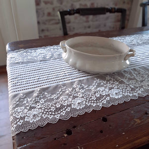 Our Old-World Lace Table Runner adds a light and breezy touch of elegance to your home. This sheer lace runner has a dreamy quality and creates instant vintage charm that is perfect for country cottage living. Translucent white lace is embroidered with a floral design along the edges with stripes down the center. Blend of cotton, linen and polyester. 15.7”W x 78.7”L