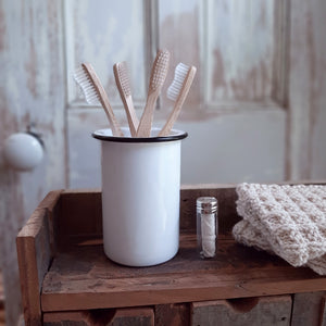 Perfect for creating instant vintage charm in any bathroom, our Vintage Style Enamelware Toothbrush Holder is inspired by flea market finds. It holds four brushes and the lid is easily removed for cleaning. Features a white enamel finish with black rim, which gives this piece a timeless feel.  (wood toothbrushes sold separately)