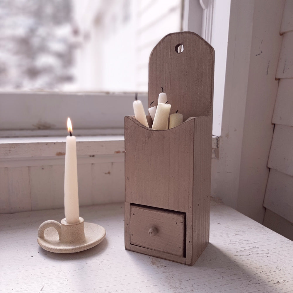 Our Wood Candle Box with Drawer is a sweet storage solution for taper candles. Its weathered antique white finish makes it perfect for any room in your farmhouse. Features a wooden box with one small drawer for stashing away matches. The Candle Box includes a pre-drilled hole so that it can be hung on the wall, or it can also be displayed tabletop. Measures 12.25" high, 4.25" wide, and 3.25" deep.